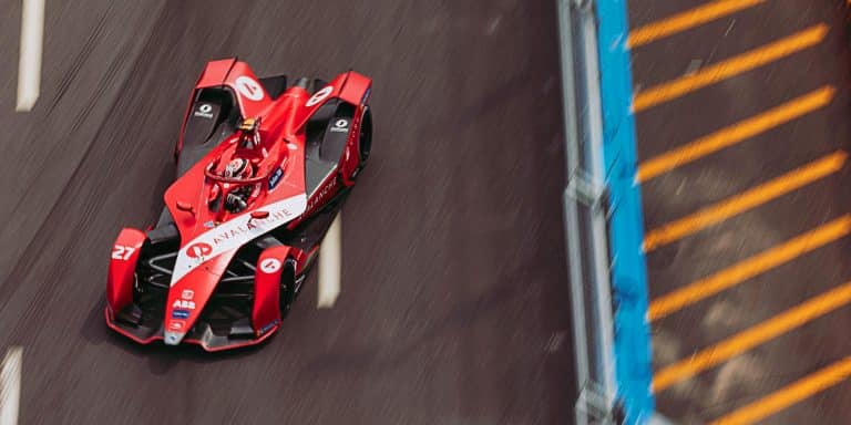Monoplace de Formule E en piste lors d'un E-Prix, vue de dessus, avec les logos des sponsors sur la carrosserie