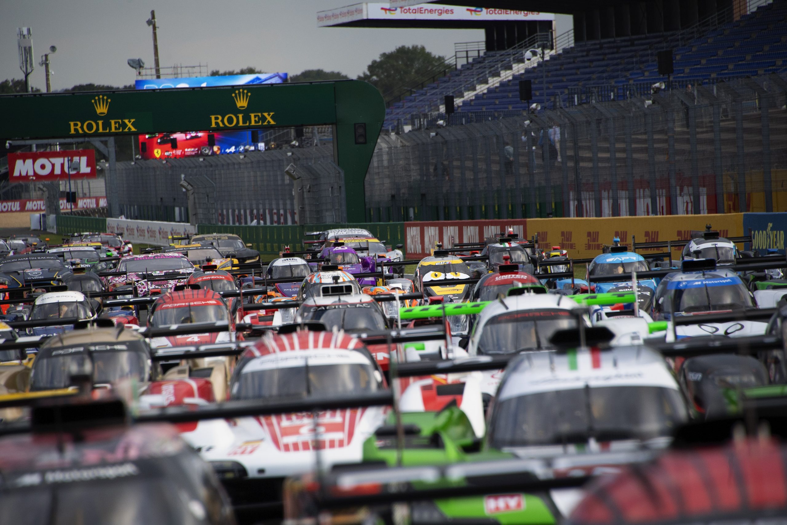 Prototipe dan mobil GT WEC berjajar di lintasan lurus pit Le Mans, di bawah jembatan berlogo Rolex