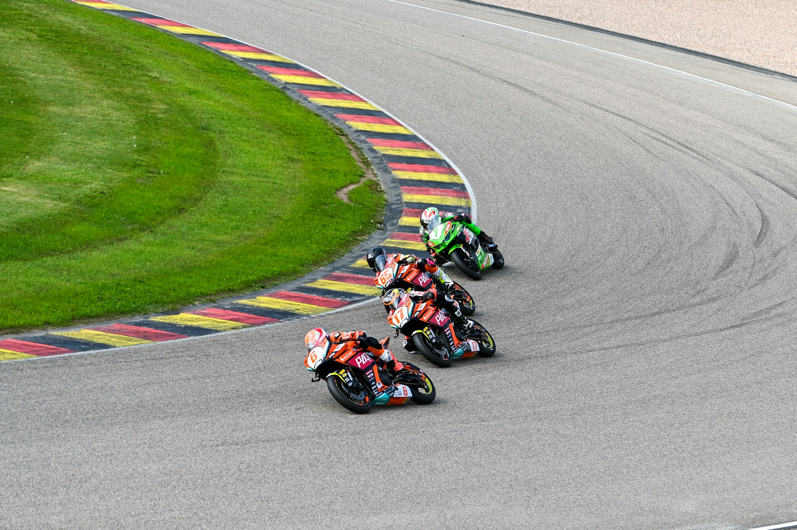A motorcycle leaned over in a left-hand corner, with kerbs in the colours of the German flag