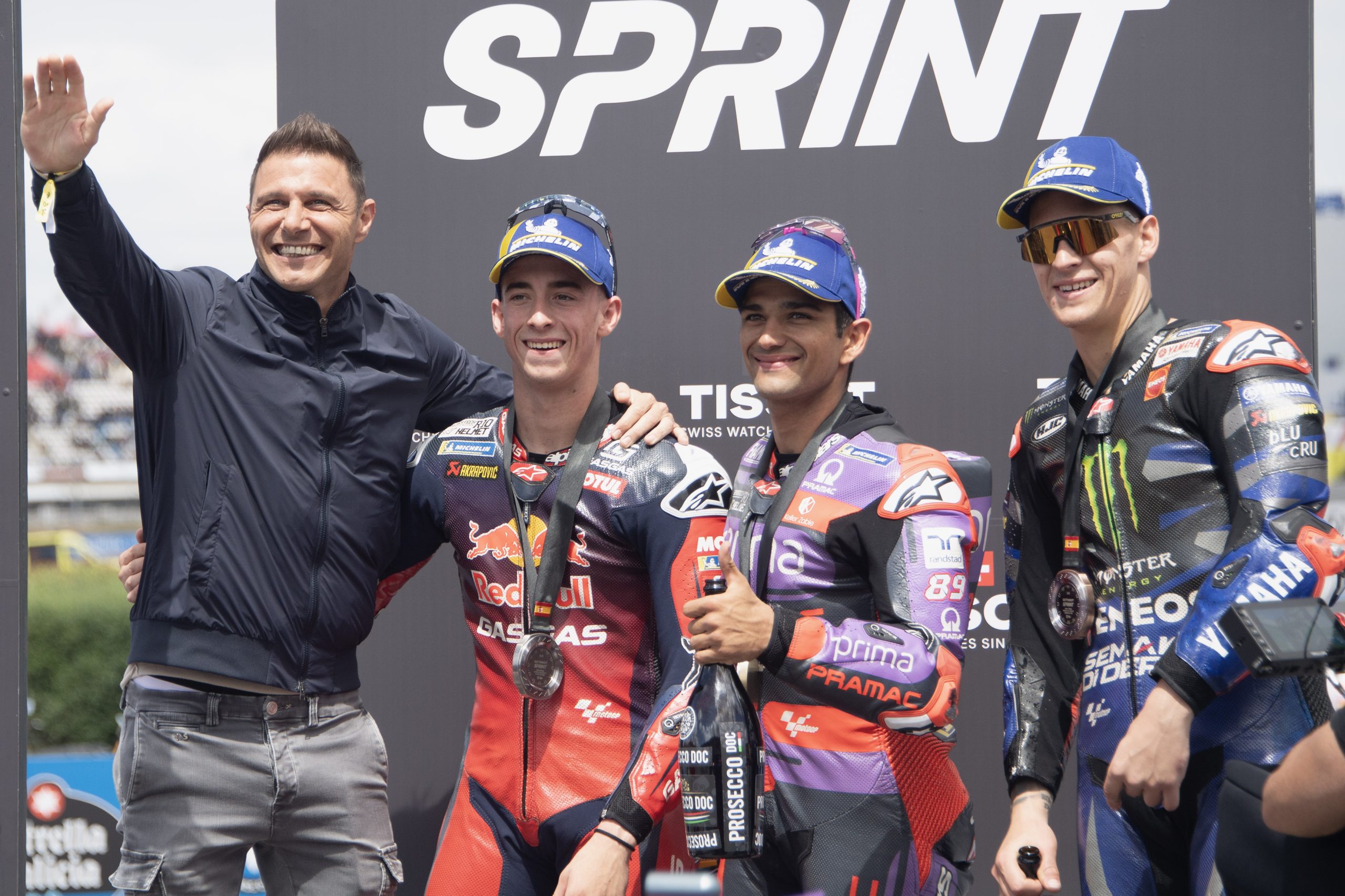 MotoGP-Fahrer auf dem Podium des Sprints von Jerez 2024, in mit Sponsorenlogos bedeckten Anz&uuml;gen