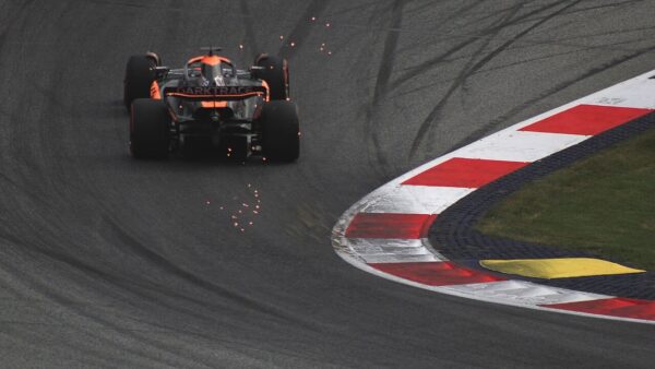 Bolid McLaren Formuły 1 w zakręcie, widziany od tyłu, z iskrami spod podłogi